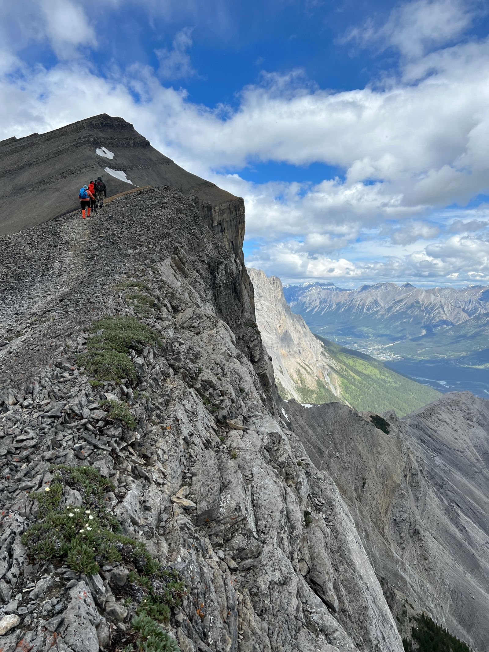 Wandelaars op een rotsachtige bergkam boven een bewolkte vallei